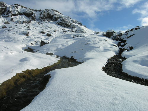 Two streams flowing through snow covered rocky terrain